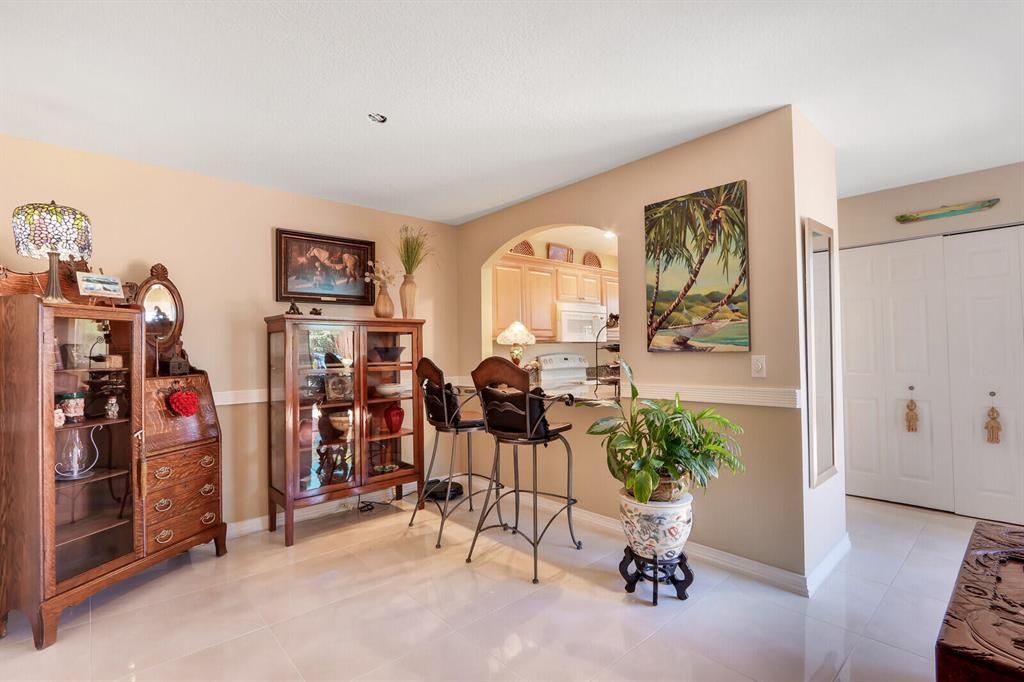 Dining area with a high-top table, wooden display cabinets, and an arched opening to the kitchen.