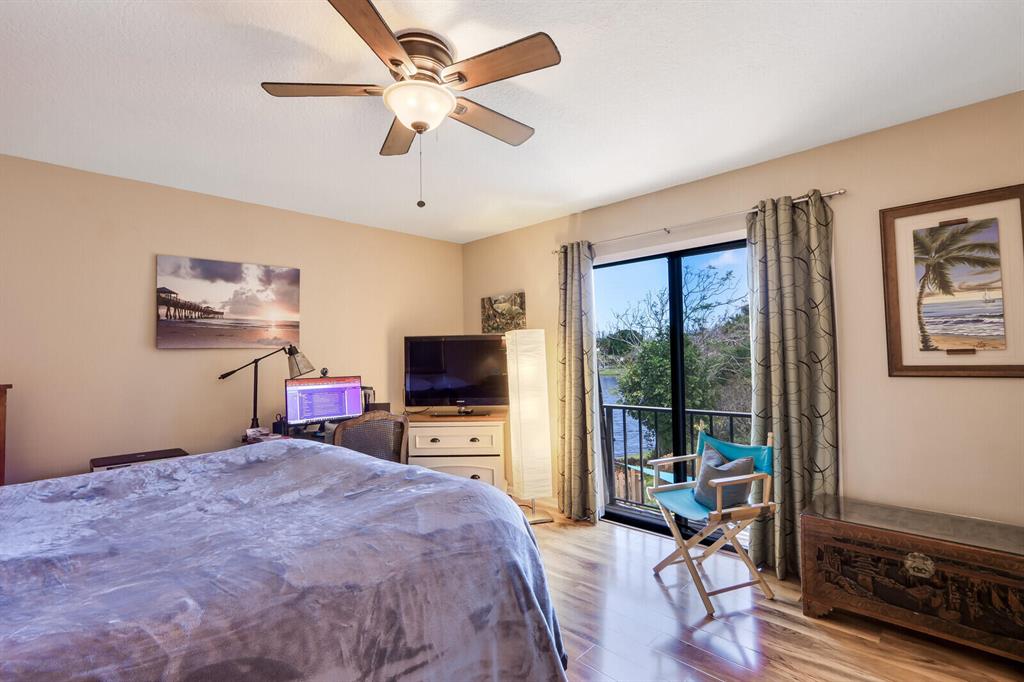 Bedroom with a large bed, desk, ceiling fan, and sliding glass doors opening onto a balcony.