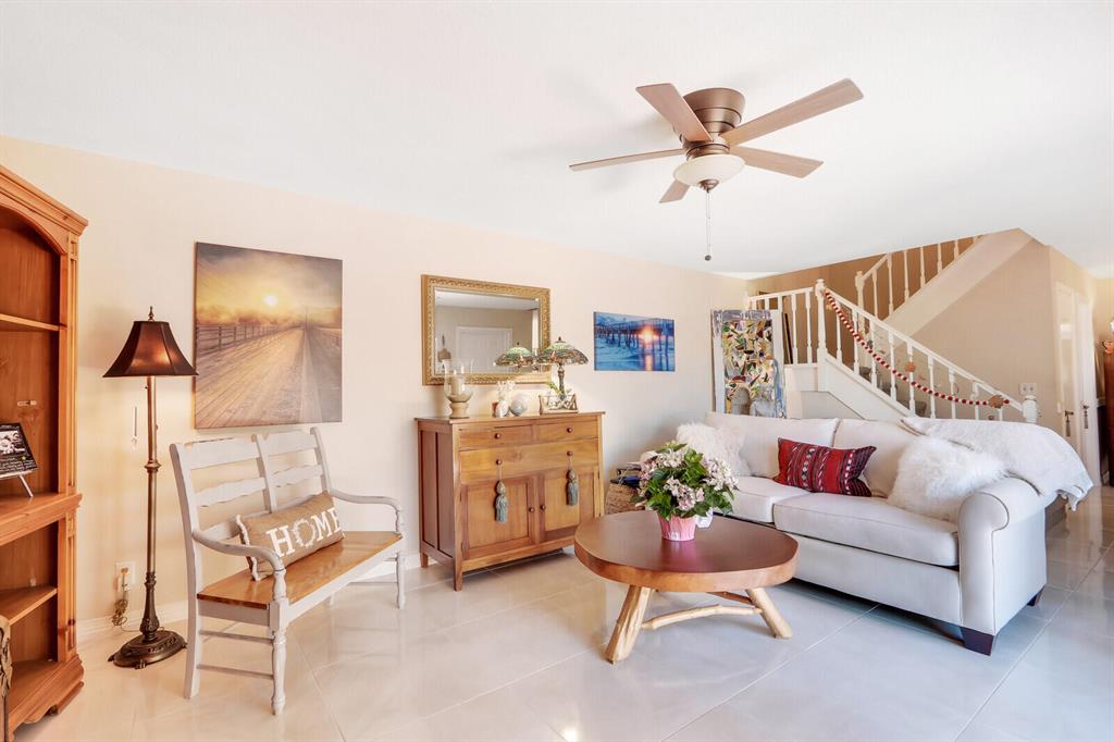 Living room with a white sofa, round wooden coffee table, and staircase with white railings.
