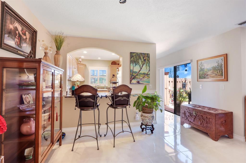 Dining area with two bar-height chairs, a glass-front display cabinet, and an open sliding door.