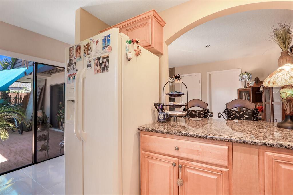 Kitchen with granite counters and light wood cabinets beside sliding doors to a covered patio.