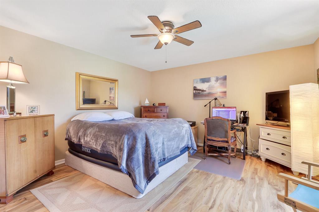 Bedroom with a large bed, ceiling fan, and computer desk.