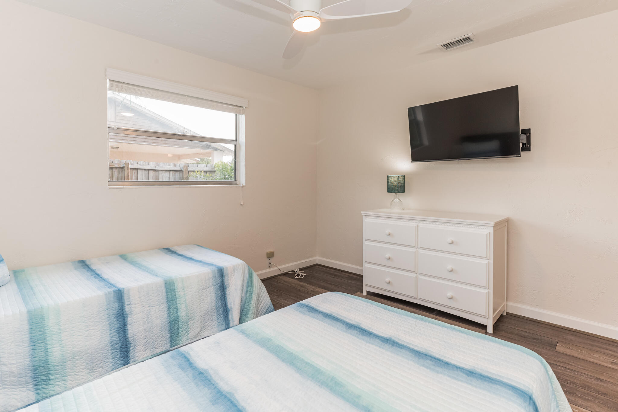 Bedroom with two blue-and-white striped twin beds, a white dresser, and a wall-mounted television.