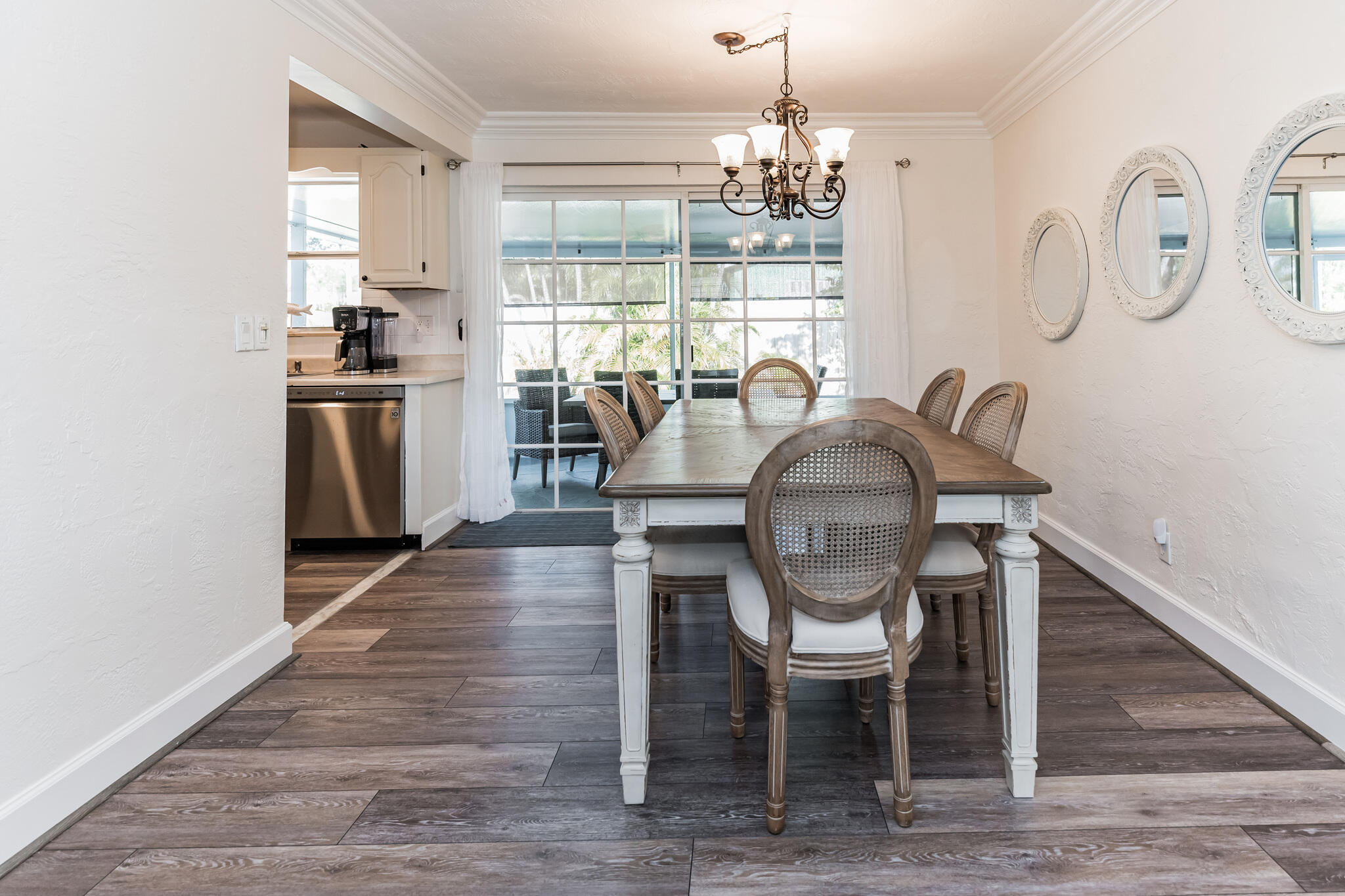 Dining room with a long wood table, cane-back chairs, and sliding glass doors to a patio.