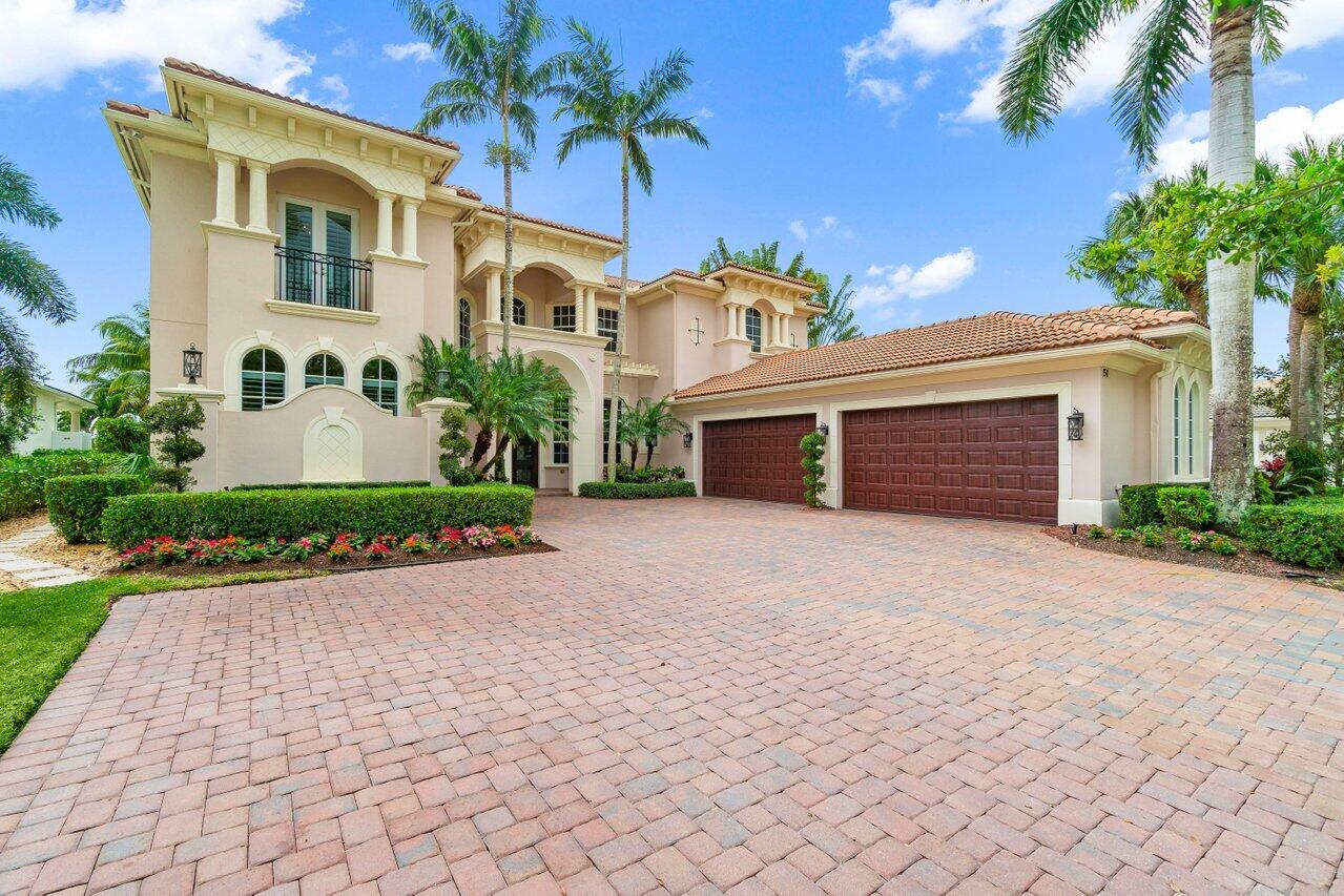 Two-story peach stucco home with arched details, a red tile roof, and a three-car garage.