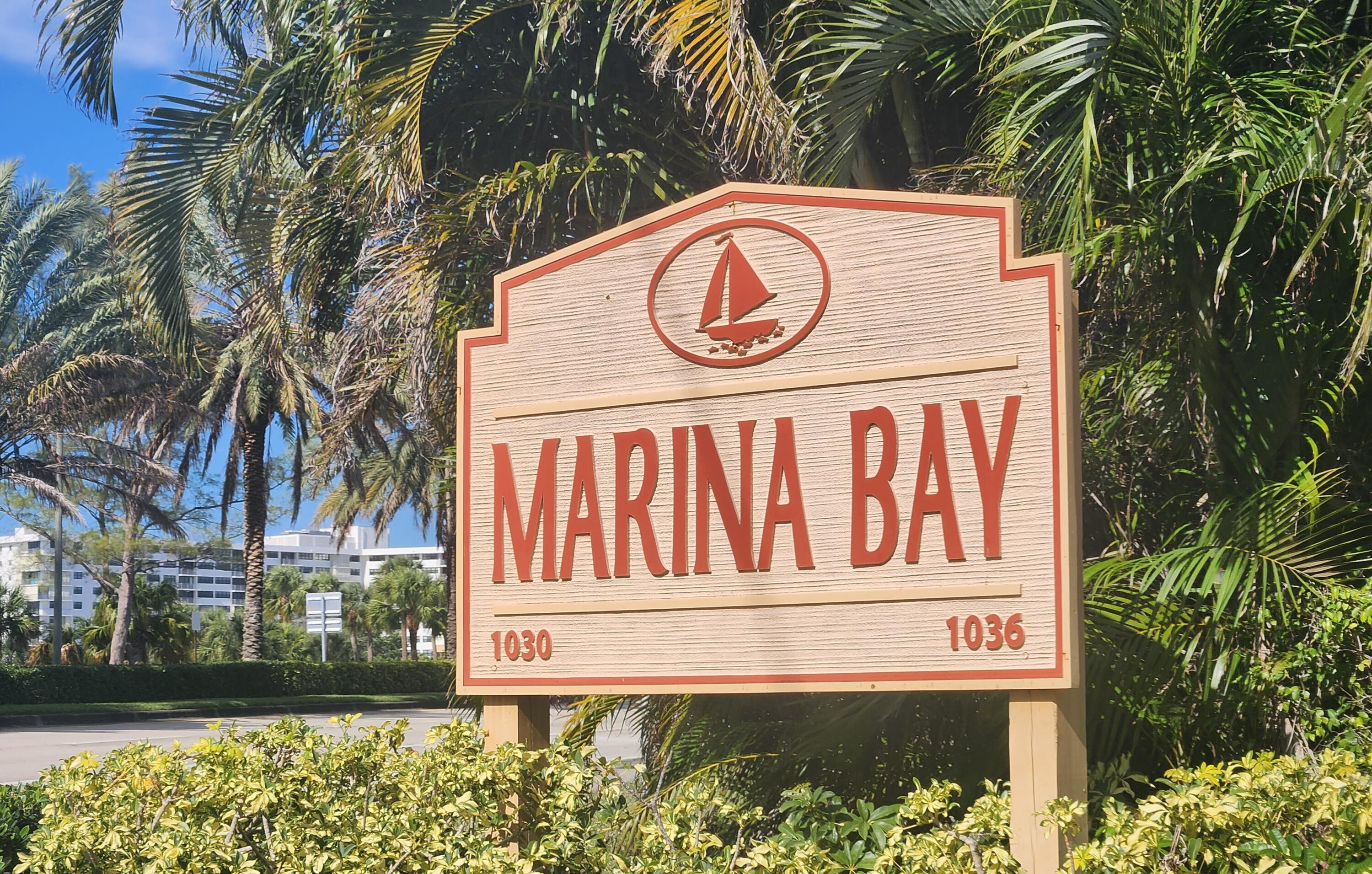 Marina Bay entrance sign with a sailboat emblem, framed by palm trees.