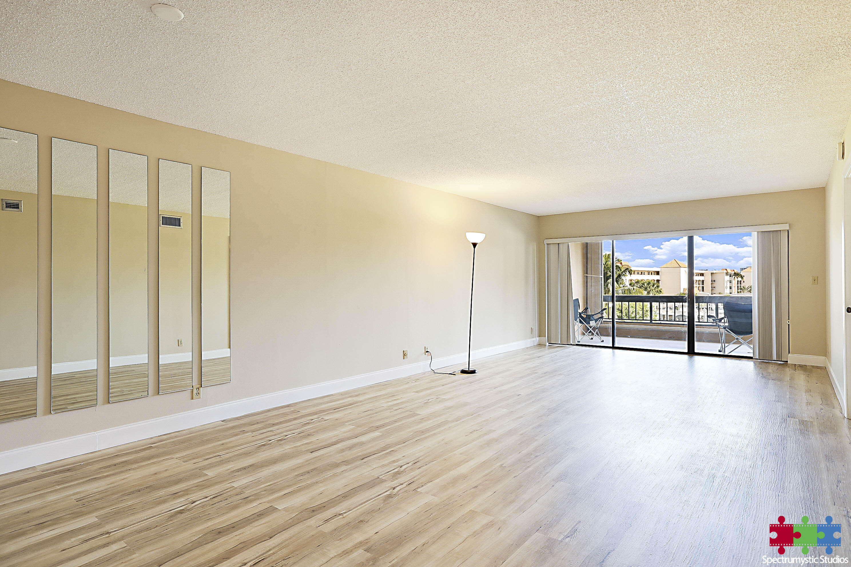 Vacant living room with mirrored wall and sliding doors to a balcony.