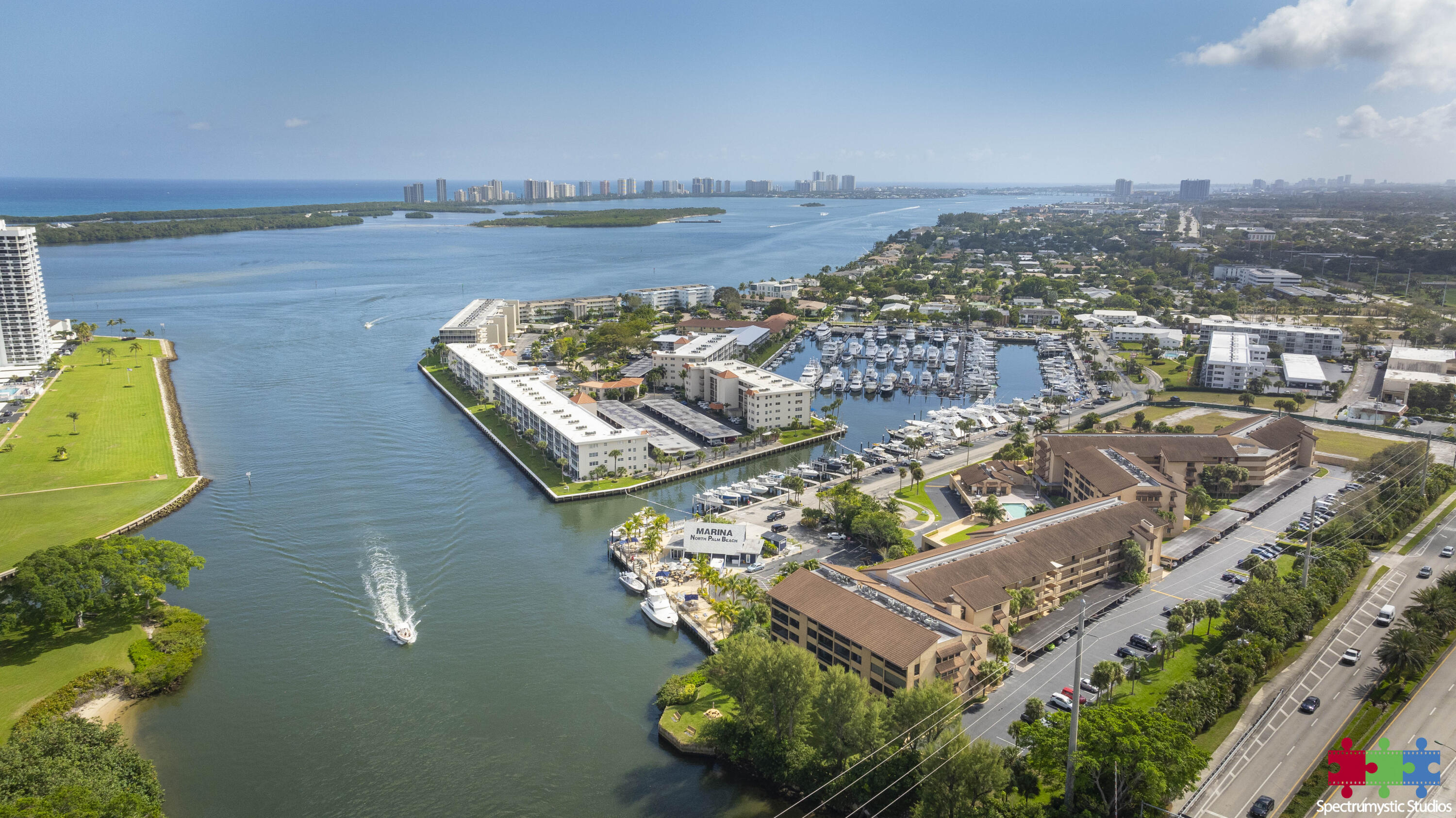 Aerial view of North Palm Beach marina and waterfront condos, with boats and a highway along the shore.