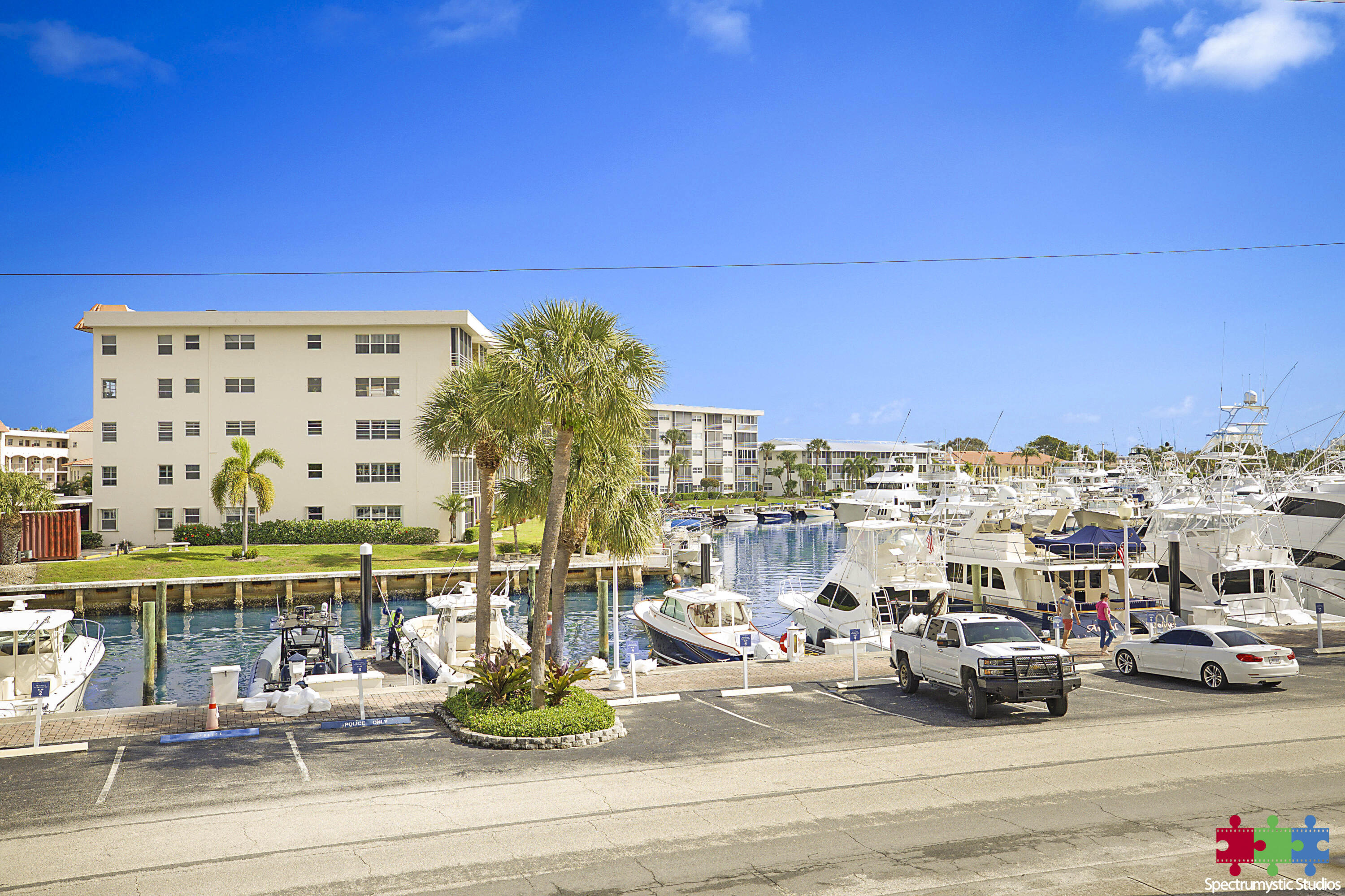 Condominium beside a marina crowded with boats, viewed across the waterfront docks and parking area.