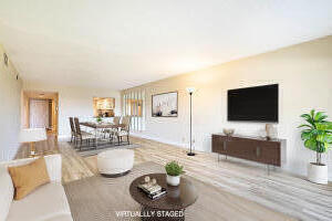 Virtually staged living room with a wall-mounted television and light tile floors.