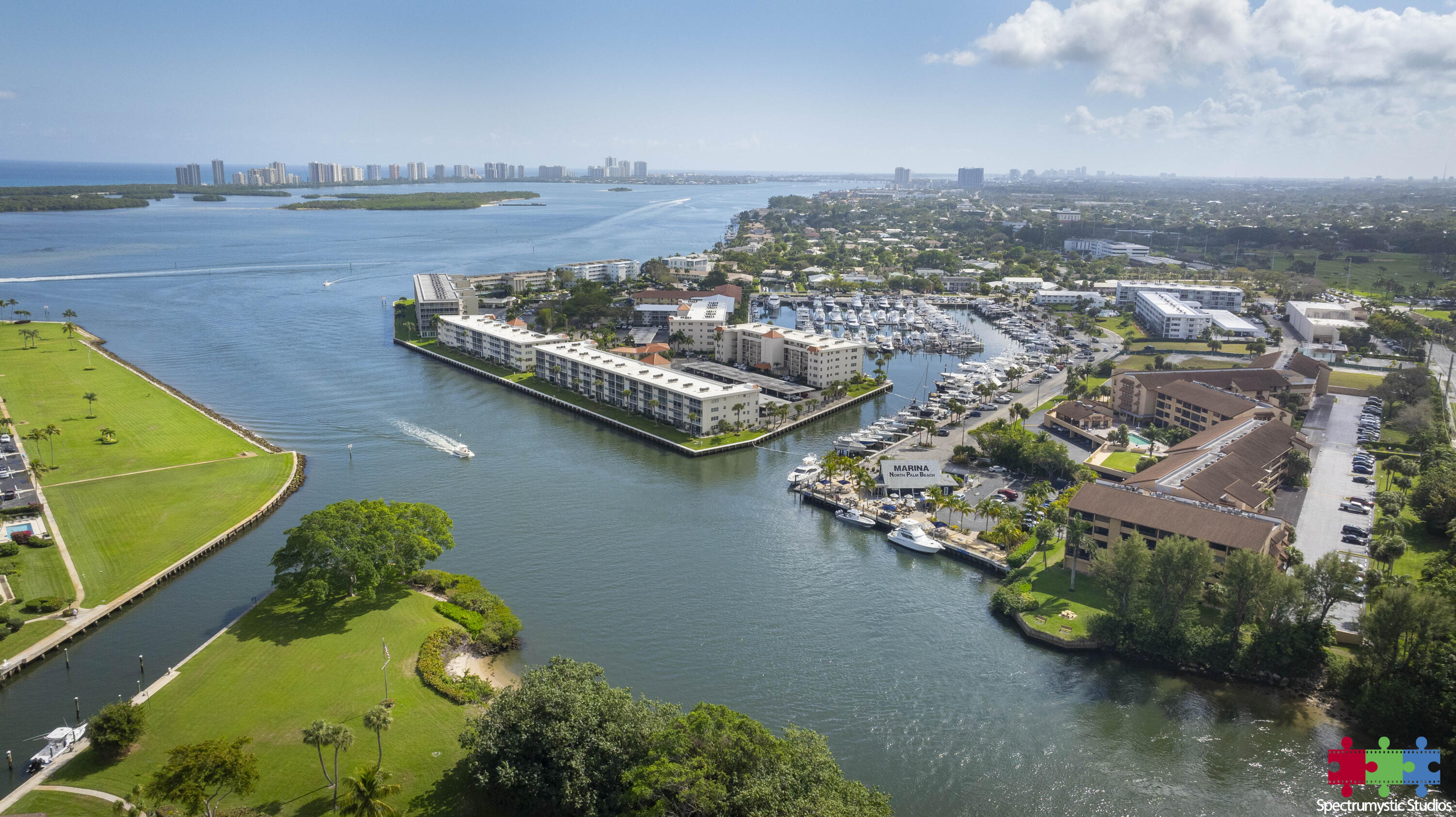 Aerial view of North Palm Beach marina, waterfront condominiums, boats, and a green shoreline park.