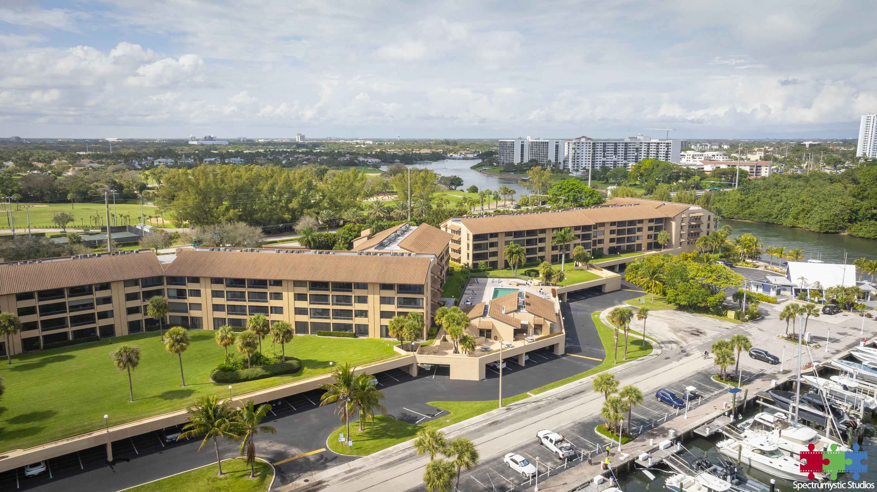 Waterfront condominium complex with a marina, boats, palm trees, and a waterway beyond.