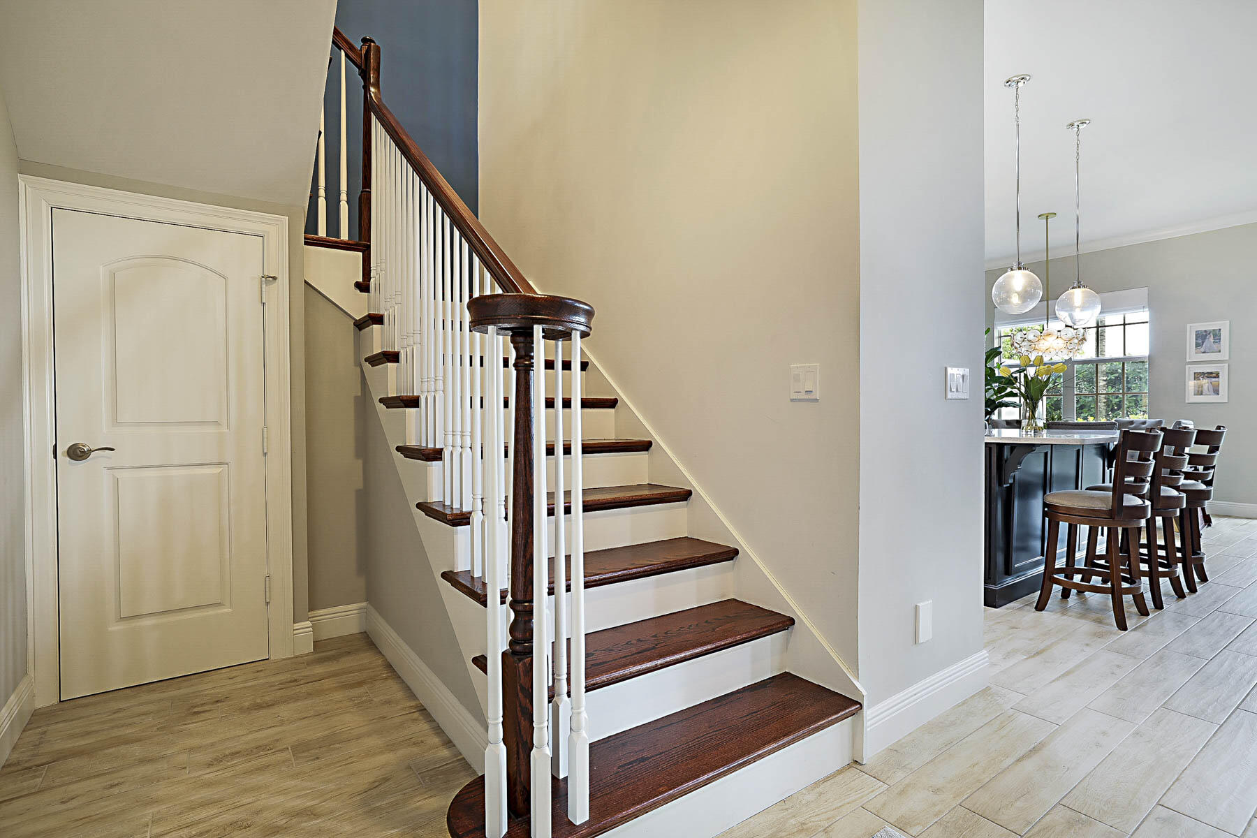 Entry foyer with a dark wood staircase and an adjoining dining area with large windows.
