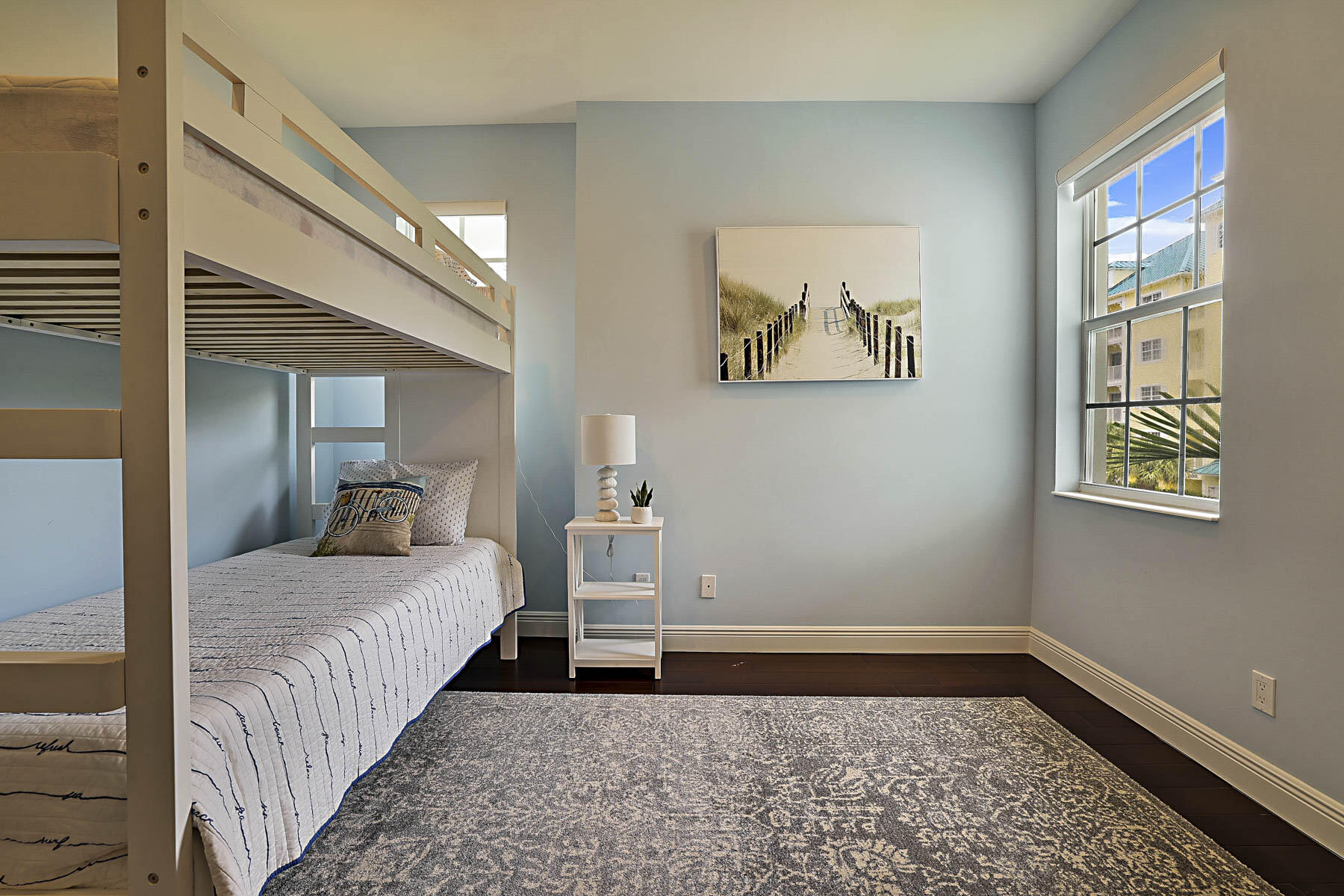 Bedroom with built-in bunk beds, pale blue walls, and a large sunlit window.