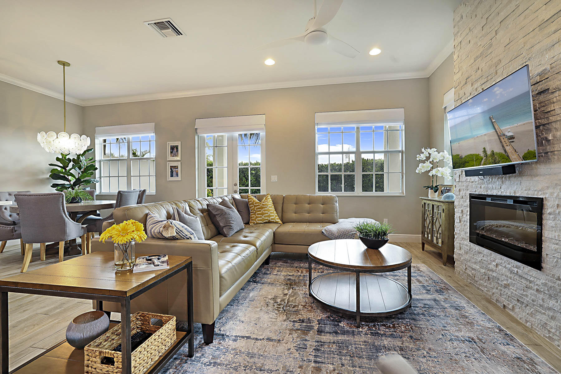 Living room with a tan sectional, large windows, and a stone fireplace wall.
