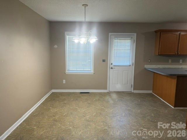 Vacant dining area beside a kitchen peninsula, with tile flooring and a door with blinds.