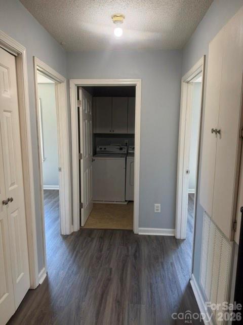 Hallway leading to a laundry area, with gray wood-look floors and white doors.