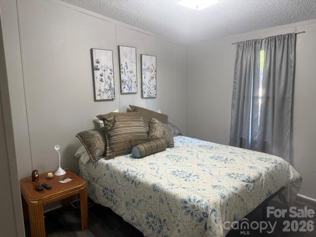 Furnished bedroom with a blue floral bedspread, layered pillows, and gray window curtains.