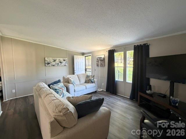 Living room with two light sofas, a large television, and dark curtains framing bright windows.