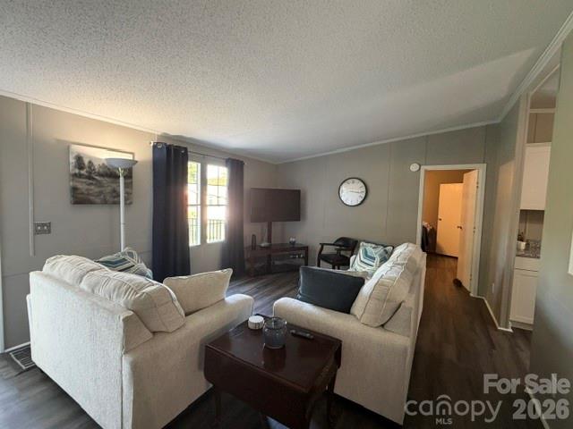 Living room with white sofas, a dark coffee table, hardwood floors, and a window with dark curtains.