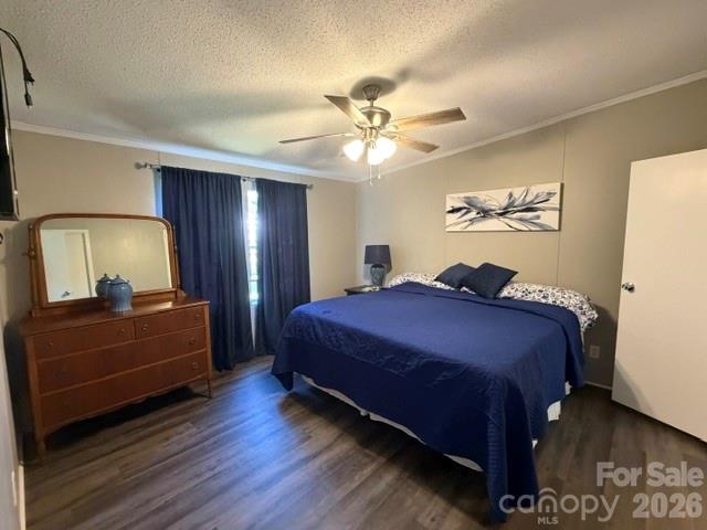 Bedroom with navy bedding, wooden dresser and mirror, and dark wood-look flooring.