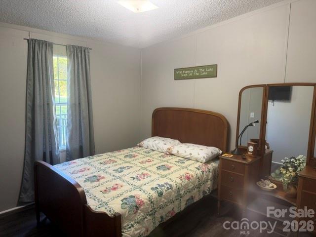 Furnished bedroom with a dark wood bed, floral quilt, and matching dresser with mirror.