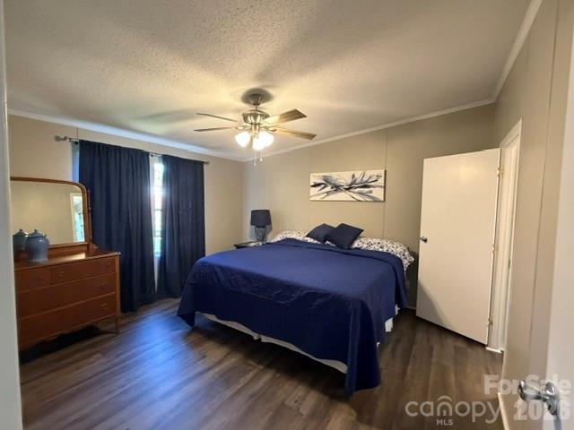 Bedroom with a navy-covered bed, dark curtains, and a wooden dresser with mirror.