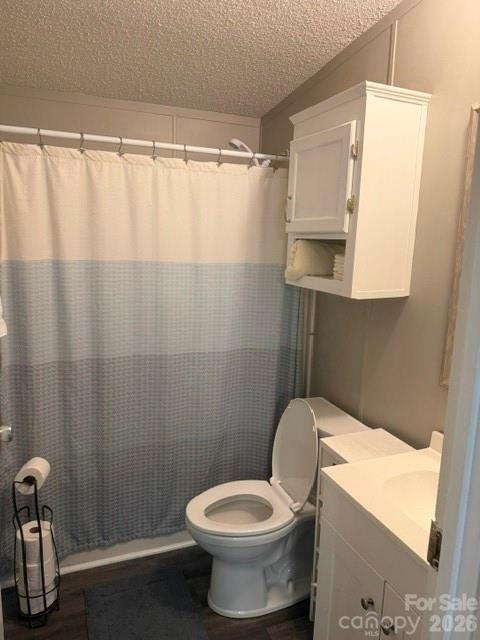 Bathroom with a blue-and-white shower curtain, toilet, and white vanity.