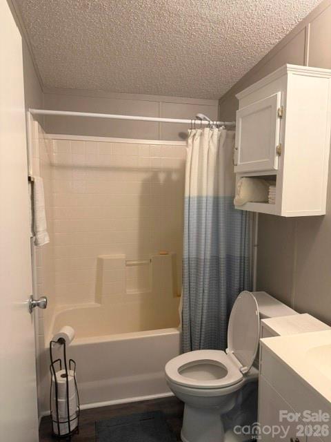 Bathroom with a tub, blue-gray shower curtain, toilet, and wall-mounted cabinet.
