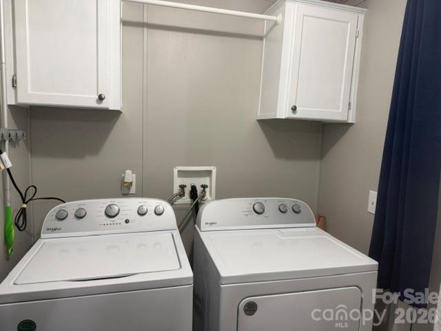 Laundry room with a top-loading washer, front-loading dryer, and overhead cabinets.