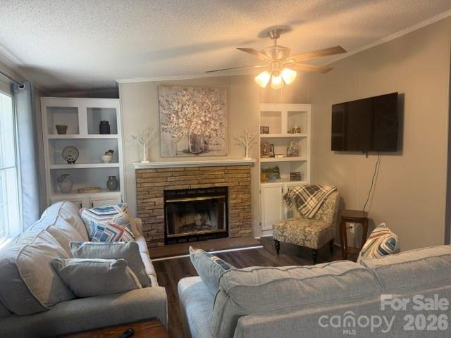 Living room with a stone fireplace, built-in shelves, gray sofas, and a wall-mounted TV.