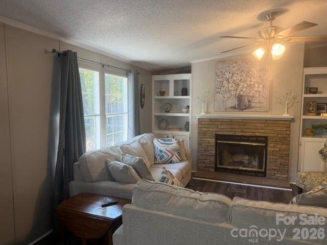 Furnished living room with sectional sofas, built-in shelves, and a stone fireplace.