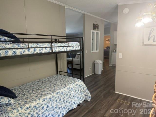 Bedroom with a black metal bunk bed, blue-and-white floral bedding, and wood-look flooring.
