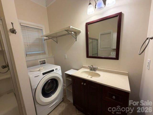 Bathroom with dark wood vanity and front-loading washer beside the shower.