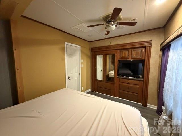 Bedroom with a bed, dark wood entertainment center, ceiling fan, and curtained window.