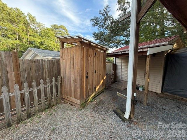 Wooden backyard shed beside a weathered picket fence and covered outbuildings.