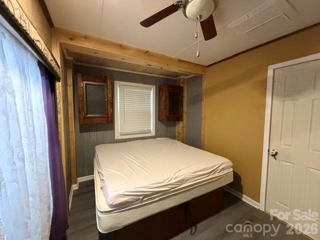 Bedroom with a bare mattress, wood ceiling beams, and small cabinets flanking the window.