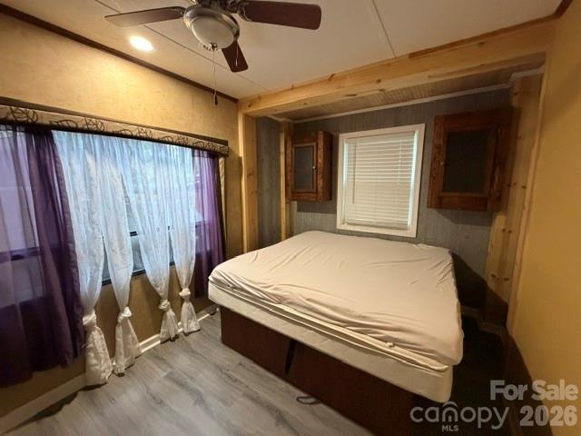 Bedroom with a mattress beneath built-in cabinets and a large curtained window.