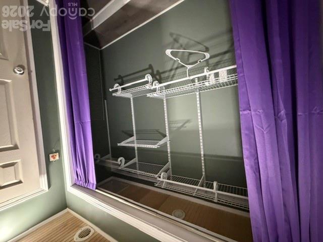 Walk-in closet with white wire shelving, hanging rods, and purple curtains.