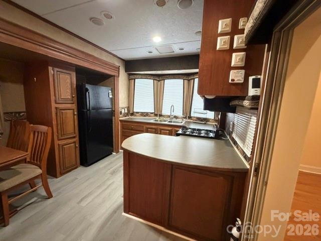 Kitchen with dark wood cabinetry, black appliances, and a rounded peninsula with a light countertop.