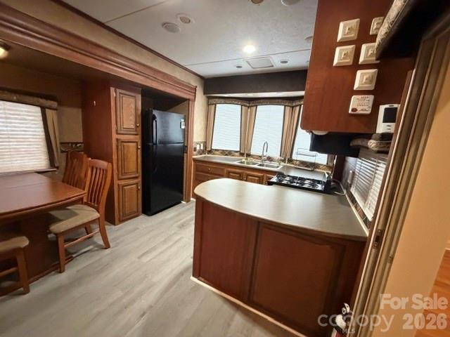 Kitchen with dark wood cabinets, a central peninsula, black appliances, and a small dining table.