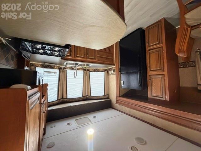 Kitchen with warm wood cabinets, black appliances, a gas cooktop, and a large curved peninsula.