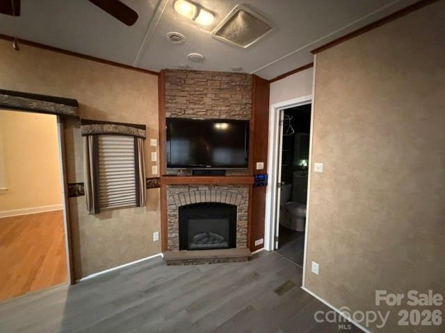 Interior room with a brick fireplace, wall-mounted television, and gray plank flooring.