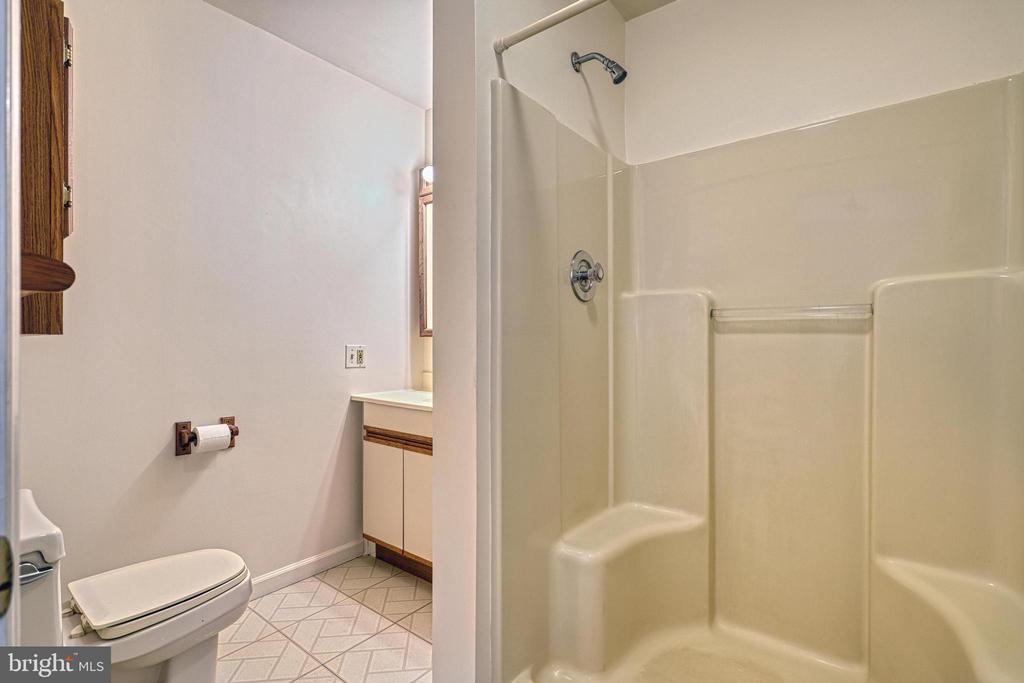 Bathroom with a molded shower enclosure, toilet, and vanity beside a small window.