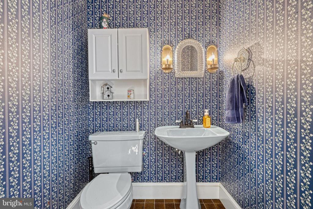 Bathroom with floral striped wallpaper, a white pedestal sink, and toilet.