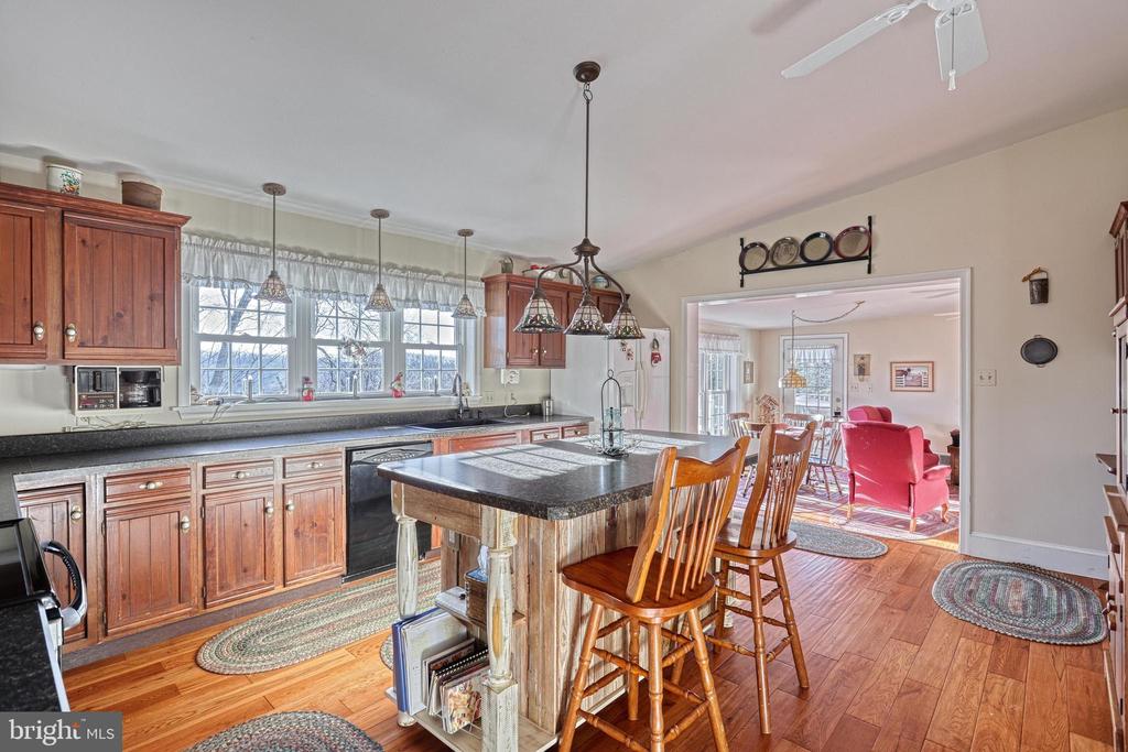 Kitchen with a wood island and bar stools opens to a living room with red seating.