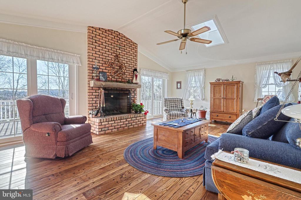 Living room with a brick fireplace, hardwood floors, large windows, and a blue sofa.