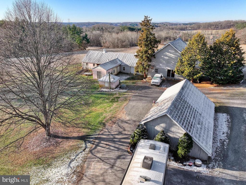 Aerial view of a rural property with several outbuildings and a driveway surrounded by leafless trees.