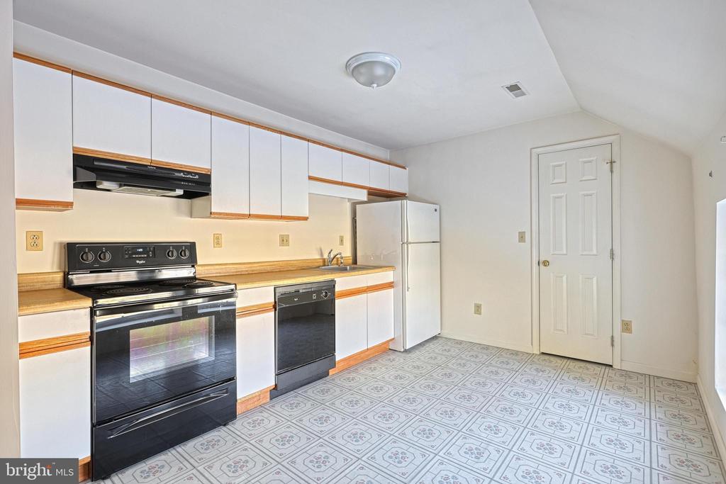 Vacant kitchen with white cabinets, black appliances, and patterned tile flooring.