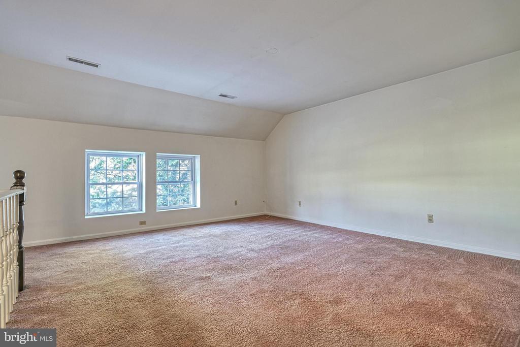 Empty carpeted bedroom with two windows and a staircase railing.